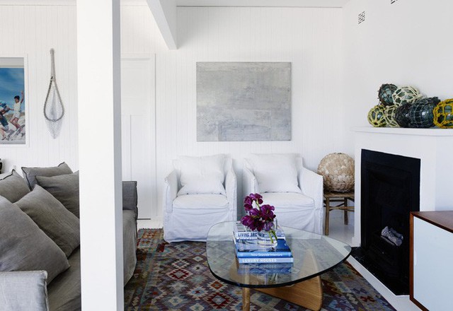 
Phòng khách nhỏ nhưng thoải mái với ghế sofa màu trắng và xám nhạt, thảm thổ cẩm đơn giản.
