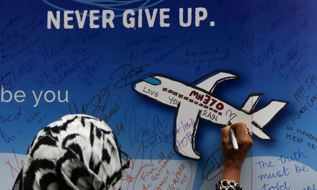 Nhiều người kí tên trên tấm bảng có hình vẽ máy bay MH370 và dòng chữ KHÔNG TỪ BỎ (Ảnh: EPA)