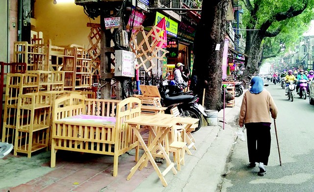 
Nhiều cơ sở buôn bán các mặt hàng đồ gỗ trên đường Đê La Thành lấn chiếm trọn vỉa hè, buộc người dân phải đi bộ dưới lòng đường.
