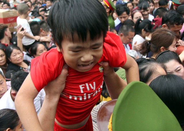 Một bé trai khóc lóc khi bị xô đẩy được lực lượng công an giải cứu khỏi đám đông.