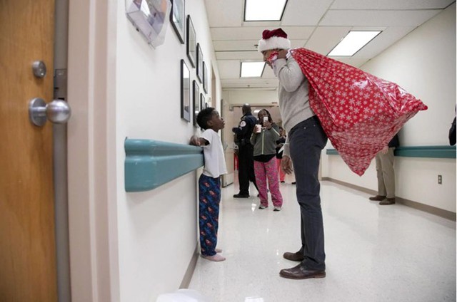 
Cựu tổng thống Obama với chiếc mũ ông già Noel trên đầu, đang nói chuyện với một cậu bé khi ông tặng quà tại một bệnh viện nhi. Ảnh: Getty Images.
