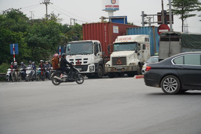Các loại xe trọng tải lớn chiếm phần lớn diện tích mặt đường, người tham gia giao thông vị ép sát vào mép đường.