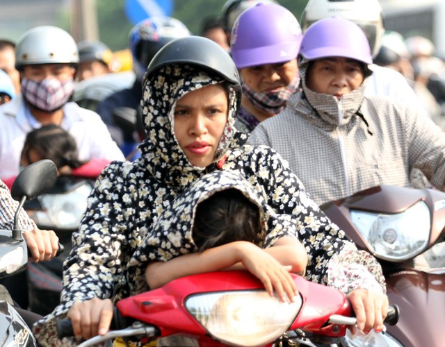 Bé gái ngủ ngon lành trên đầu xe máy của mẹ tại khu vực đường Giải Phóng.