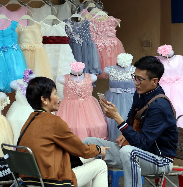
Chủ tiệm bán áo váy cho bé gái trên phố Hàng Đào cũng mặc thêm áo ấm.

