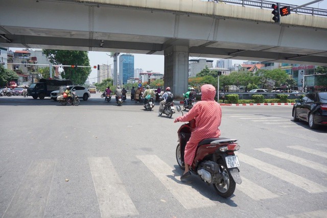 Một đoàn người đi xe máy phải vượt đèn đỏ do không thể đứng chờ 60 giây dưới trời nắng nóng.