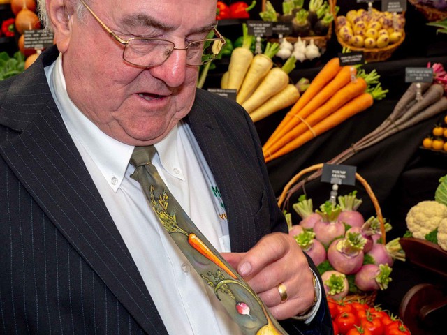 Tại khu vực trưng bày rau củ quả, một chủ cửa hàng khoe chiếc cà vạt có in hình các loại củ. Ảnh: Getty.