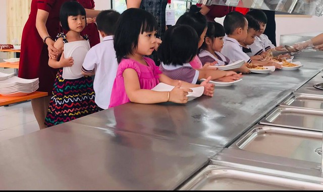 Các bé mầm non ở TP.HCM xếp hàng chờ lấy cơm khi tới giờ ăn ở trường (Ảnh: Lê Huyền)
