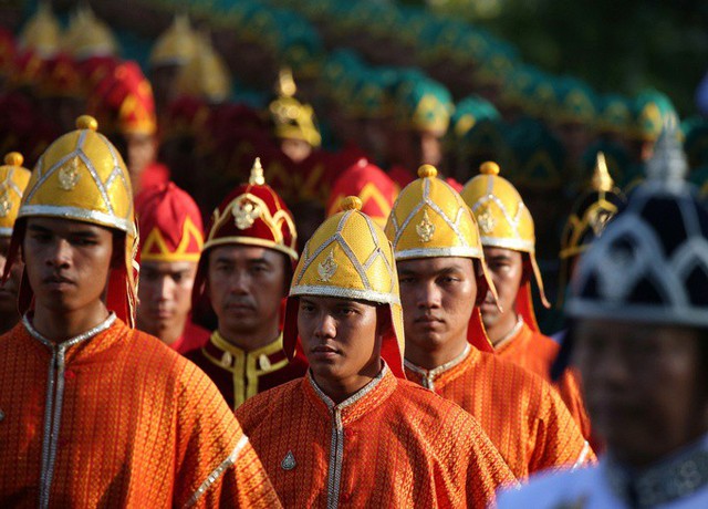 Các thành viên trong đoàn khiêng kiệu trong trang phục màu da cam. Chính quyền Thái Lan đã chi khoảng 31,3 triệu USD để tổ chức lễ đăng quang cho Vua Vajiralongkorn. Nhà chức trách ước tính đám đông tập trung xem lễ rước kiệu có khoảng 200.000 người.