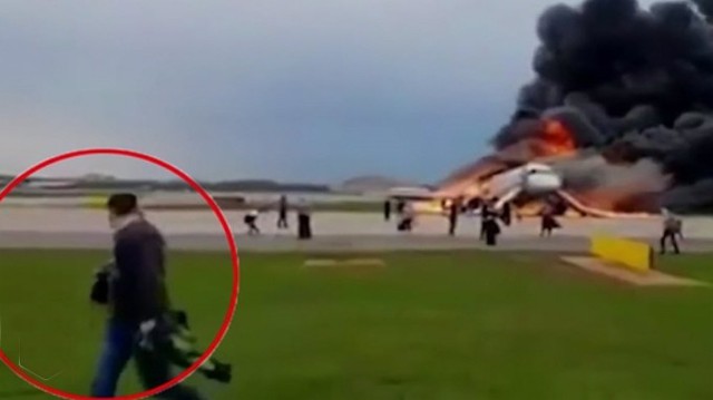 Một trong số những hành khách cầm hành lý xách tay ra khỏi chiếc máy bay bốc cháy ở Nga hôm 5/5. Ảnh: Ren TV.