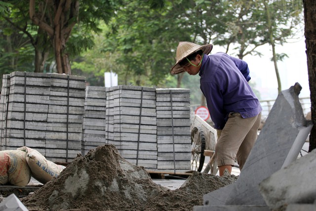 Những công nhân tại công trường cải tạo, chỉnh trang hè phố bằng đá tự nhiên, ở phố Trích Sài (quận Tây Hồ, Hà Nội).