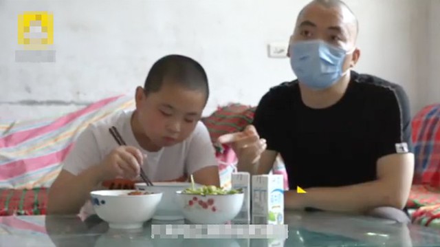 Ngồi cạnh bố Lu Yanheng, cậu bé Lu Zikuan ăn 3 bát tô và hai hộp sữa mỗi bữa. Ảnh cắt từ video.