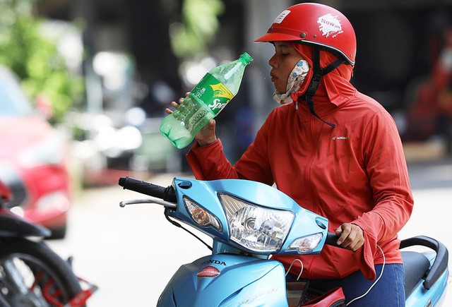 Để tránh mất nước, người phụ nữ này mang theo chai nước to, khi xuống gầm cầu Long Biên thì dừng xe lại và uống một hơi dài.