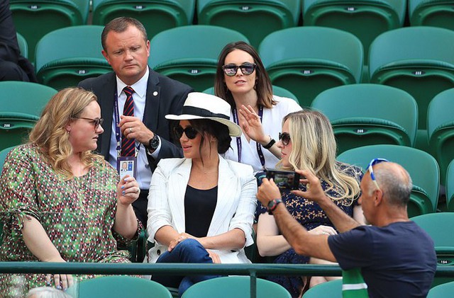 Một người đàn ông giơ máy ảnh chụp gần Nữ công tước xứ Sussex trên khán đài trận đấu giữa Serena Williams và Kaja Juvan trong khuôn khổ giải Đơn nữ Wimbledon hôm 4/7. Ảnh: PA.