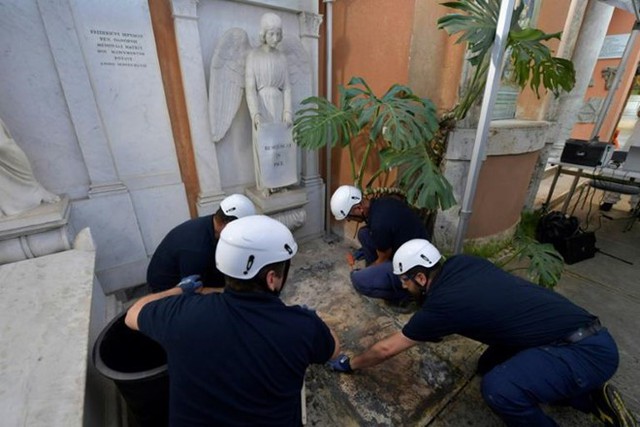 Các nhân viên mở nắp hai ngôi mộ trong nghĩa trang Teutonic ở Vatican, nơi có bức tượng thiên thần chỉ tay xuống. Ảnh: AFP.