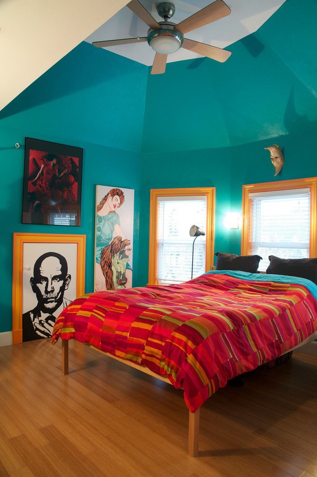 
Một phòng ngủ màu ngọc lam được tạo điểm nhấn với bộ đồ giường màu đỏ và khung cửa sổ màu vàng sáng.

