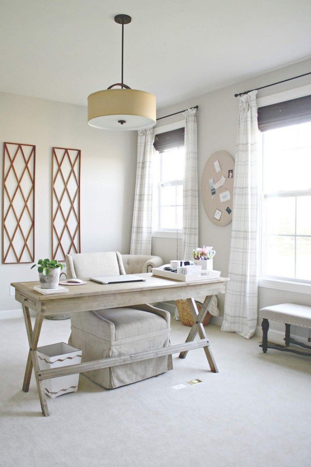 
Một phòng làm việc tại nhà có màu trung tính với chất liệu gỗ trắng, nhiều hình in và luồng ánh sáng tự nhiên mạnh chiếu vào từ các cửa sổ.
