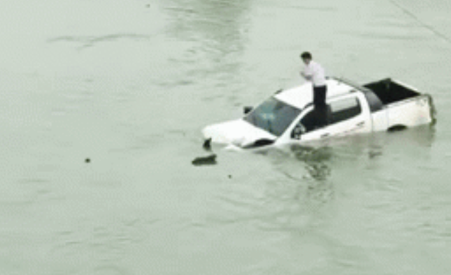 Hình ảnh tài xế trèo lên nóc xe ô tô trôi lềnh bềnh giữa sông khiến nhiều người hoang mang - Ảnh 1.