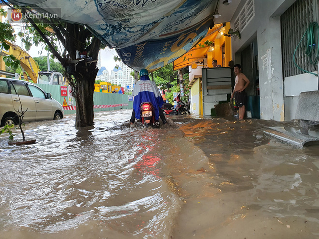 TP.HCM: S&aacute;ng nắng gắt, chiều mưa lớn kinh ho&agrave;ng khiến người d&acirc;n ướt sũng, b&igrave; b&otilde;m dắt xe lội nước - Ảnh 11.