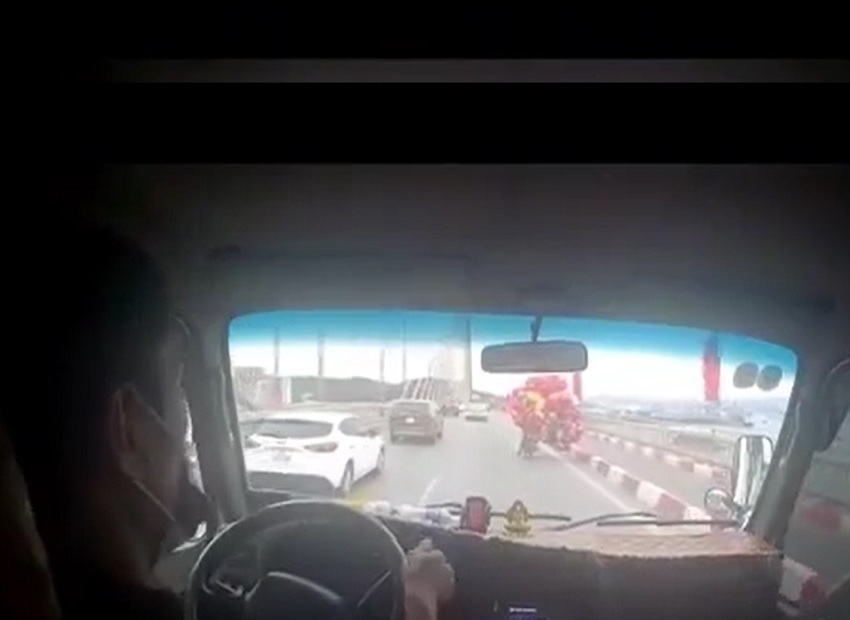 Ấm l&ograve;ng xe tải che chắn gi&oacute; cho người b&aacute;n b&oacute;ng bay đi qua cầu - Ảnh 1.