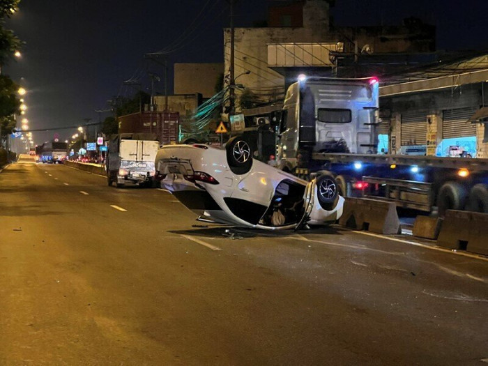 Ô tô 4 chỗ lộn nhiều vòng trên QL1, văng vào xe tải rồi lật ngửa giữa đường - Ảnh 1.