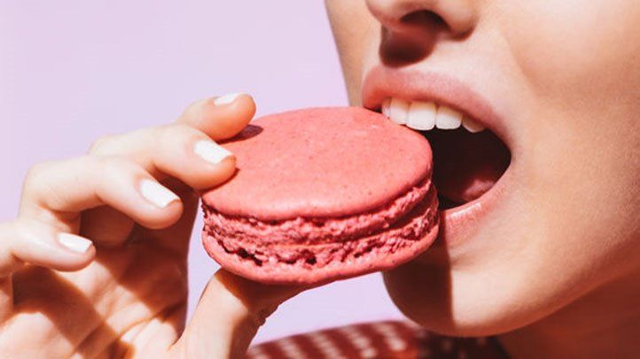 một người phụ nữ đang ăn một chiếc bánh macaron