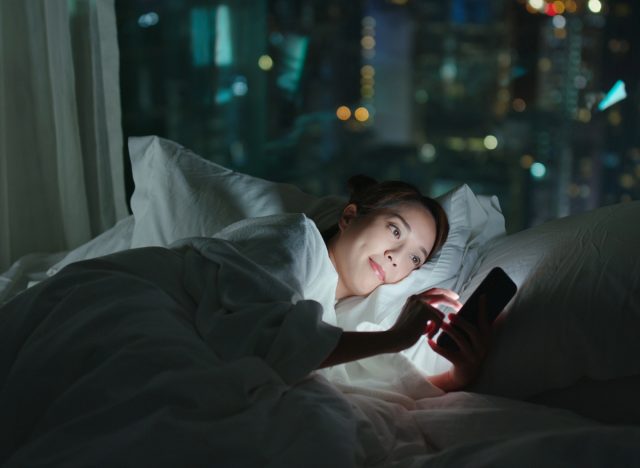 người phụ nữ lướt mạng xã hội trên giường