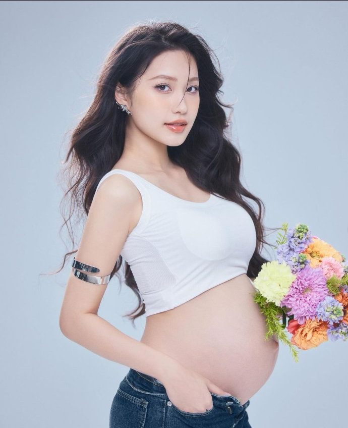 A pregnant person holding flowers  Description automatically generated