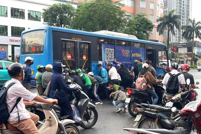 H&agrave; Nội: Người d&acirc;n hợp sức n&acirc;ng xe bu&yacute;t cứu nữ t&agrave;i xế xe m&aacute;y mắc kẹt sau va chạm - Ảnh 1.