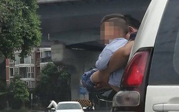 Bé trai được bế ra ngoài cửa ôtô đang chạy để đi vệ sinh