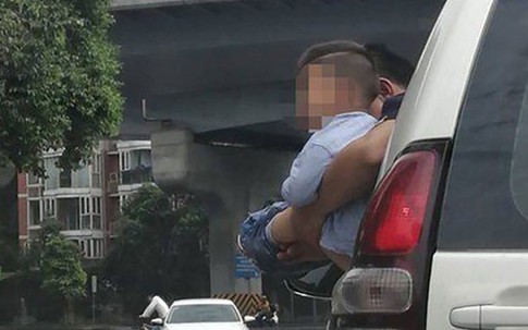 Bé trai được bế ra ngoài cửa ôtô đang chạy để đi vệ sinh