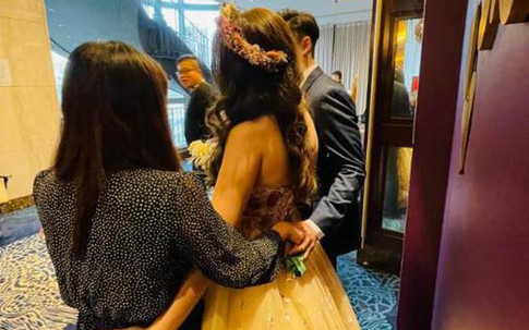 Bạn thân cô dâu nắm tay chú rể sau lưng khi cùng chụp ảnh tại đám cưới